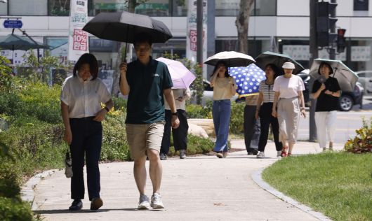서울 낮 최고기온이 37도를 기록하는 등 전국 대부분 지역에 폭염이 기승을 부린 지난달 29일 서울 송파구 석촌호수 인근에서 양산을 쓴 시민들이 더위를 피해 발걸음을 옮기고 있다. 조현호 기자 hyunho@