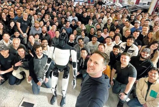 자신이 개발을 주도한 휴머노이드 로봇 옵티머스를 앞에 두고 동료 직원들과 기념 촬영을 하고 있는 밀란 코박 전 부사장(맨 앞 서 있는 이). 현대차그룹은 16일 그를 자문역으로 영입했다고 밝혔다.
