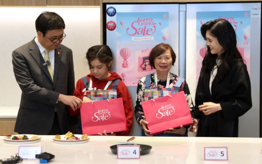 최휘영 문화체육관광부 장관이 22일 서울 영등포구 더현대 서울 문화센터에서 진행되고 있는 코리아그랜드세일의 체험행사 '케이-소스 활용 한식 쿠킹클래스'에 이부진 한국방문의해위원회 위원장과 함께 참여해 외국인 관광객에게 선물을 전달하고 있다.