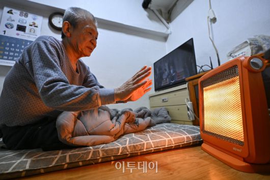 영하 10도 안팎의 한파가 닷새째 이어진 23일 서울 용산구 동자동 쪽방촌에서 한 주민이 이불과 전기난로로 추위를 피하고 있다. 조현호 기자 hyunho@