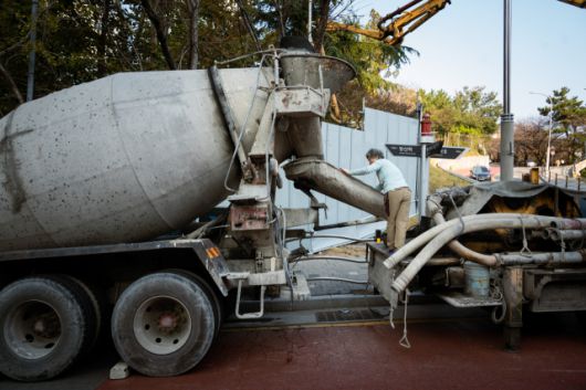 ▲<프레시안>은 지난달 24일 부산 기장군의 한 건설현장을 찾아 레미콘 기사로 25년째 일하고 있는 정정숙씨를 만났다. 레미콘을 운반하자마자 레미콘이 흐른 자리에 붙어 굳지 않도록 통로를 긁어내는 정숙씨. ⓒ황지현