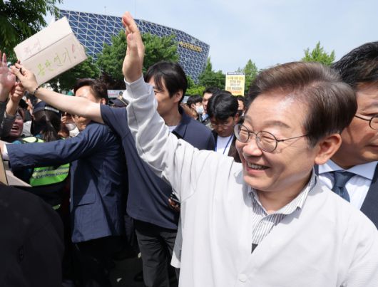 ▲더불어민주당 이재명 대선 후보가 '골목골목 경청투어:국토종주편'에 나선 7일 전북 전주시 풍남문 앞 광장에서 지지자가 든 공판 연기 환영 팻말을 지나고 있다. 이날 서울고등법원은 오는 15일 예정됐던 이 후보의 공직선거법 위반 혐의 사건 파기환송심 첫 공판을 오는 6월 18일로 연기했다. ⓒ연합뉴스