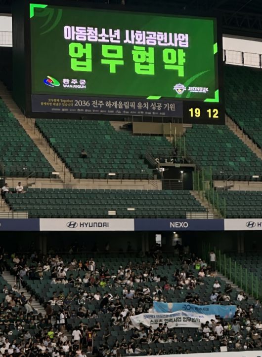 ▲전주월드컵경기장 전광판에 ‘완주군-전북현대 아동청소년 사회공헌사업 업무협약’ 문구가 송출되고 있는 가운데, 완주군 아동·청소년들이 관중석에서 경기를 관람하고 있다. ⓒ완주군