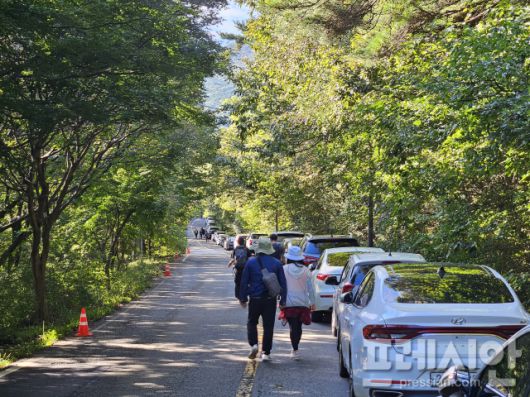 ▲9일 광주 북구 금곡동 원효사 가는 도로에 길게 주차된 차량들이 길게 늘어선 가운데 등산객들이 걸어가고 있다.2025.10.09ⓒ프레시안(김보현)