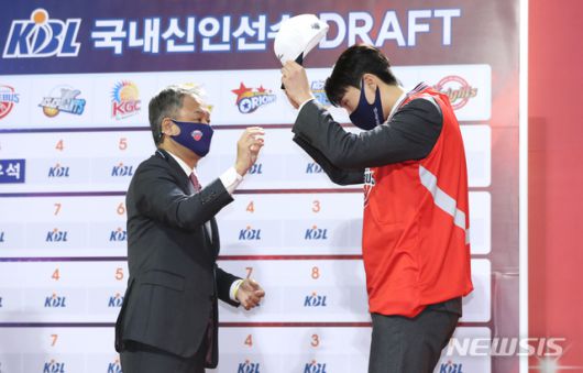 [서울=뉴시스]이윤청 기자 = 23일 서울 송파구 잠실학생체육관에서 열린 2020 KBL 국내신인선수 드래프트에서 전체 1라운드 3순위로 울산현대모비스에 지명된 고려대 이우석이 유니폼, 모자 등을 착용하고 있다. 왼쪽은 유재학 감독. 2020.11.23. radiohead@newsis.com
