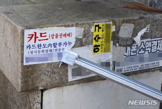 [서울=뉴시스] 백동현 기자 = 성북구 거리환경지킴이들이 서울 성북구 장위로 인근에서 벽에 붙은 불법사금융업체 광고 스티커를 떼고 있다. 2021.10.13. livertrent@newsis.com