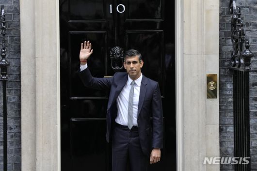 [런던=AP/뉴시스]리시 수낵 신임 영국 총리가 25일 언던 다우닝가 10번지 계단에서 손을 흔들고 있다. 수낵은 이날 버킹엄궁에서 찰스 3세 영국 국왕으로부터 정부 구성을 요청받아 새 총리가 됐다. 2022.10.25