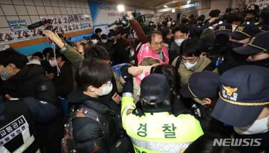 [서울=뉴시스] 조수정 기자 = 전국장애인차별철폐연대(전장연)가 13일 오전 서울 삼각지역 승강장 앞에서 '시민과 함께하는 달보기 운동' 선언 기자회견을 마친 뒤 승강장 바닥에 부착한 선전물이 비가 오면 미끄러우니 떼라는 지하철 공사 측의 요청에 락카로 '미끄럼 주의' 문구를 써놓으려다 제지하는 지하철공사 직원들과 몸싸움을 하고 있다. 전장연은 3월 23일까지 출근길 지하철 타기 선전전을 하지 않고 기획재정부가 3월 국가재정전략회의에서 2024년 정부 예산 가이드라인을 편성할 때 장애인 권리예산이 의미있는 수준으로 반영할 것을 촉구하며 기재부 장관이 적극적으로 대화에 나서기를 기다리겠다고 밝혔다. 2023.02.13. chocrystal@newsis.com