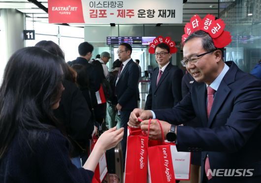 [서울=뉴시스] 최동준 기자 = 조중석 이스타항공 대표(오른쪽)과 유상종 경영총괄 전무, 이경민 커머셜본부장 및 승무원들이 26일 오전 김포국제공항 국내선 탑승 게이트에서 승객들에게 기념 굿즈를 전달하고 있다. 이스타 항공은 오늘부터 김포-제주 노선을 시작으로 3년 만에 운항을 재개했다. (공동취재사진) 2023.03.26. photo@newsis.com