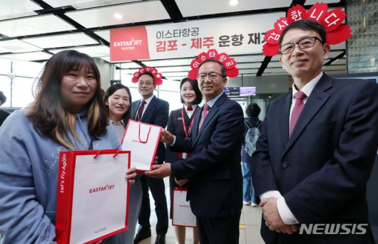 [서울=뉴시스] 최동준 기자 = 조중석 이스타항공 대표(오른쪽 두번째)과 유상종 경영총괄 전무, 이경민 커머셜본부장 및 승무원들이 26일 오전 김포국제공항 국내선 탑승 게이트에서 승객들에게 기념 굿즈를 전달하고 있다. 이스타 항공은 오늘부터 김포-제주 노선을 시작으로 3년 만에 운항을 재개했다. (공동취재사진) 2023.03.26. photo@newsis.com