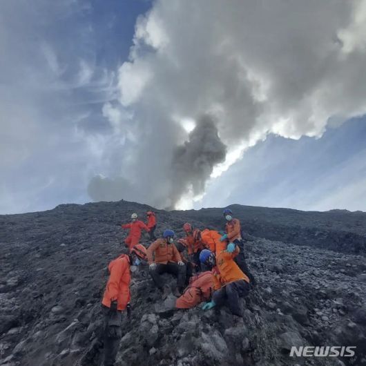 [아감=AP/뉴시스] 5일(현지시각) 인도네시아 국립수색구조국(BASARNAS)이 공개한 사진에 구조대원들이 수마트라섬 아감에서 므라피 화산 폭발로 숨진 한 등산객의 시신을 수습하고 있다. 므라피 화산 경사면을 수색하던 구조대는 이틀 전 화산 폭발로 고립됐다가 숨진 등산객의 시신을 더 찾아내 사망자 숫자는 13명이 됐다. 2023.12.05.