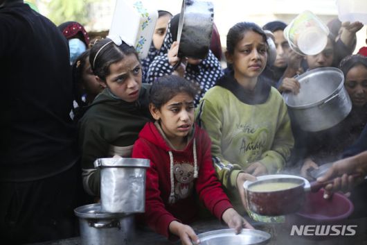 [라파=AP/뉴시스] 20일(현지시각) 가자지구 남부 라파의 급식소에 무료 음식을 받으려는 팔레스타인 어린이들이 몰려들어 음식을 받고 있다. 2023.12.21.