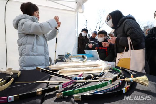 [서울=뉴시스] 권창회 기자 = 설날인 10일 오후 서울 중구 남산골한옥마을에서 열린 '청룡이 복 나르샤' 설축제에서 시민들이 활을 만들고 있다. 2024.02.10. kch0523@newsis.com