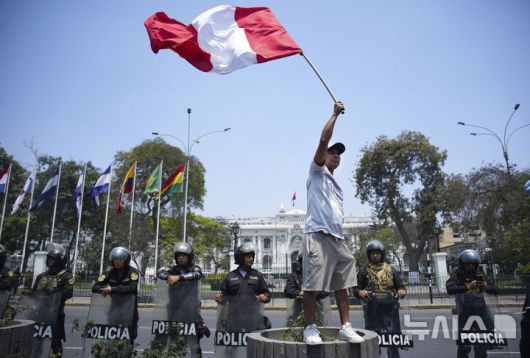 [리마=AP/뉴시스] 23일(현지시각) 페루 리마 국회의사당 앞에서 한 남성이 불안한 치안에 항의하며 국기를 흔들고 있다. 2024.10.24.