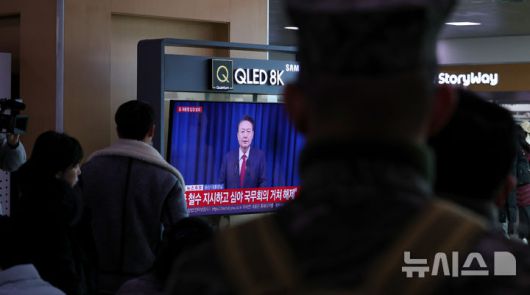 [서울=뉴시스] 추상철 기자 = 7일 오전 서울 용산구 서울역에서 시민들이 윤석열 대통령의 대국민 담화 TV를 시청하고 있다. 2024.12.07. scchoo@newsis.com