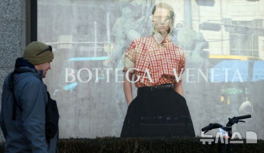 [서울=뉴시스] 고범준 기자 = 4일 한 시민이 서울의 한 백화점 앞에 설치된 보테가베네타 광고판 앞으로 지나가고 있다. 명품 브랜드 보테가베네타(Bottega Veneta)는 일부 가방 및 지갑 제품 중심으로 약 10% 가격을 올린다고 밝혔다. 2025.02.04. bjko@newsis.com