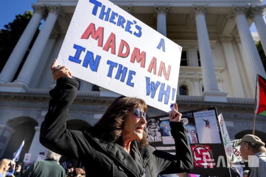 [새크라멘토=AP/뉴시스]  미 캘리포니아주 새크라멘토의 주 의사당 앞에서 한 여성이 "백악관에 웬 미친사람이 있다"는 손팻말을 들고 반트럼프 시위에 참여하고 있다.  2025.05.25.