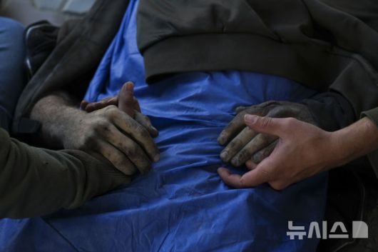 [가자시티=AP/뉴시스] 18일(현지 시간) 가자지구 가자시티 병원에서 한 가족이 이스라엘군 공습으로 사망한 팔레스타인인의 손을 잡고 있다. 2025.03.18.