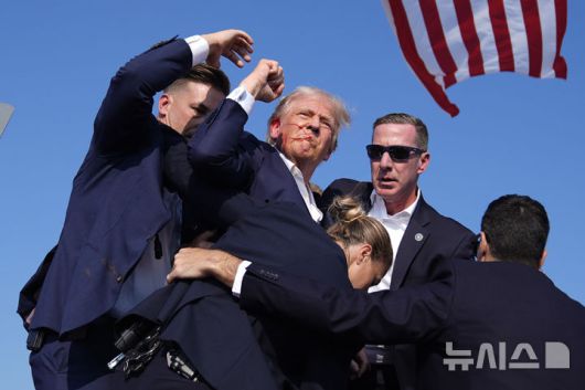 [버틀러=AP/뉴시스] 도널드 트럼프 미국 대통령이 공화당 대선 후보 시절인 지난해 7월 13일(현지 시간) 펜실베이니아주 버틀러에서 선거 유세 도중 암살 시도로 오른쪽 귀에서 피를 흘리는 모습. 2025.04.14.