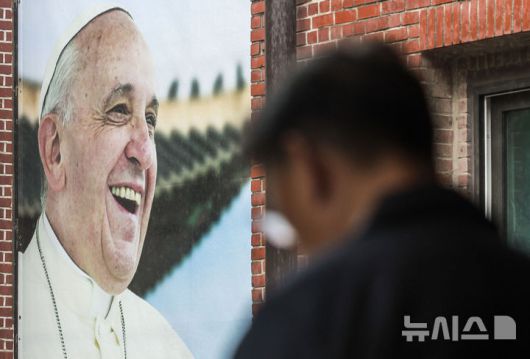 [서울=뉴시스] 정병혁 기자 = 제266대 교황인 프란치스코 교황이 선종한 가운데 22일 서울 중구 명동대성당 영성센터에서 신도들이 외벽에 걸린 프란치스코 교황 사진 앞을 지나고 있다.  2025.04.22. jhope@newsis.com