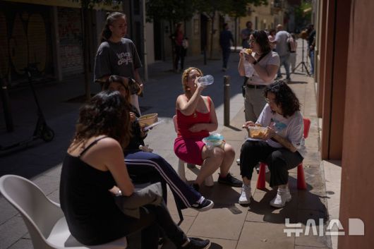 [바르셀로나=AP/뉴시스] 28일(현지 시간) 스페인에서 대규모 정전 사태가 발생하자 바르셀로나의 한 상점 직원들이 상점 밖으로 나와 점심을 먹고 있다. 이날 스페인과 포르투갈에서 발생한 대규모 정전으로 기차, 지하철, 항공기 등 주요 교통수단이 마비되며 피해가 잇따랐다. 2025.04.29.