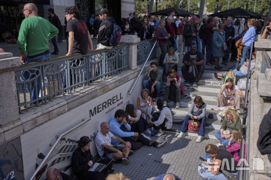 [바르셀로나=AP/뉴시스] 28일(현지 시간) 스페인에서 대규모 정전 사태가 발생해 바르셀로나 시민들이 폐쇄된 지하철역 밖에서 운행 재개를 기다리고 있다. 이날 스페인과 포르투갈에서 발생한 대규모 정전으로 기차, 지하철, 항공기 등 주요 교통수단이 마비되며 피해가 잇따랐다.  2025.04.29.