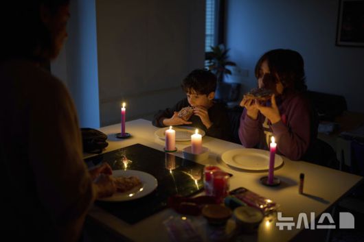 [바르셀로나=AP/뉴시스] 28일(현지 시간) 스페인에서 대규모 정전 사태가 발생하자 바르셀로나의 한 가정집에서 가족이 촛불을 켜놓고 식사하고 있다. 이날 스페인과 포르투갈 전역에서 발생한 대규모 정전으로 기차, 지하철, 항공기 등 주요 교통수단이 마비되며 피해가 이어졌다. 2025.04.29.