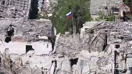 [카미얀카=AP/뉴시스] 지난달 28일(현지 시간) 러시아 군인 2명이 우크라이나 하르키우주 카미얀카의 한 건물 위에 러시아 국기를 게양하고 있다. 2025.05.26.