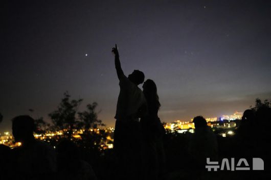[리스본=AP/뉴시스] 28일(현지 시간) 포르투갈에서 전국적인 정전 사태가 발생하자 리스본이 내려다보이는 전망대에 있던 한 연인이 밤하늘을 바라보고 있다. 2025.04.29.