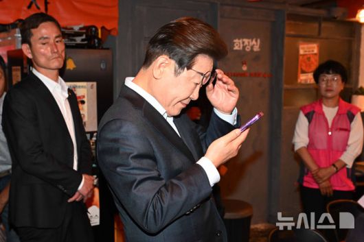 [서울=뉴시스] 조성우 기자 = 이재명 더불어민주당 대선후보가 1일 오후 서울 종로구의 한 포장마차에서 열린 비전형 노동자 간담회를 마친 뒤 휴대전화를 확인하고 있다. 대법원 전원합의체는 이날 이 후보에게 무죄를 선고한 원심 판결을 파기하고 사건을 서울고법으로 돌려보냈다. (공동취재) 2025.05.01. photo@newsis.com