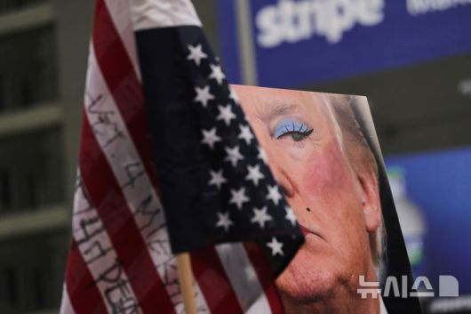 [로스앤젤레스=AP/뉴시스] 1일(현지 시간) 미국 캘리포니아주 로스앤젤레스에서 열린 노동절 시위 중 도널드 트럼프 대통령을 조롱하는 풍자 사진이 보이고 있다. 2025.05.02.