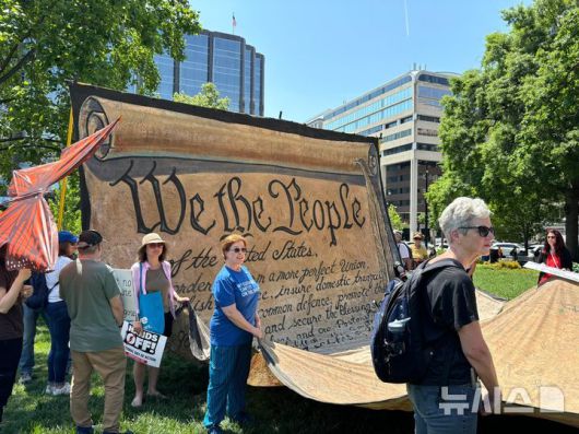 [워싱턴=뉴시스]이윤희 특파원 =국제 노동절인 1일(현지 시간) 미국 전역에서는 도널드 트럼프 행정부에 반대하는 집회가 동시다발적으로 벌어진 가운데, 미국 워싱턴DC 백악관 인근 프랭클린 공원에서 열린 '메이 데이' 집회에서 미국 헌법 모양의 대형 천막을 참가자들이 들어올리고 있다. 2025.05.02.