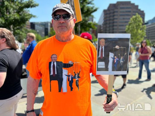 [워싱턴=뉴시스]이윤희 특파원 =국제 노동절인 1일(현지 시간) 미국 전역에서는 도널드 트럼프 행정부에 반대하는 집회가 동시다발적으로 벌어진 가운데, 미국 워싱턴DC 백악관 인근 프랭클린 공원에서 열린 '메이 데이' 집회에 글렌(48)씨가 트럼프 대통령과 머스크, 블라디미르 푸틴 러시아 대통령이 그려진 티셔츠와 그림을 들어보이고 있다. 2025.05.02.