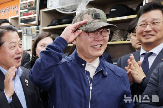 [화천=뉴시스] 조성우 기자 = 민심을 청취하는 '경청 투어'에 나선 이재명 더불어민주당 대선후보가 2일 오후 강원도 화천군 화천공영버스터미널 인근의 한 군장점에서 김병주 최고위원이 사준 병장 계급장이 달린 육군 모자를 써보고 있다. (공동취재) 2025.05.02. photo@newsis.com
