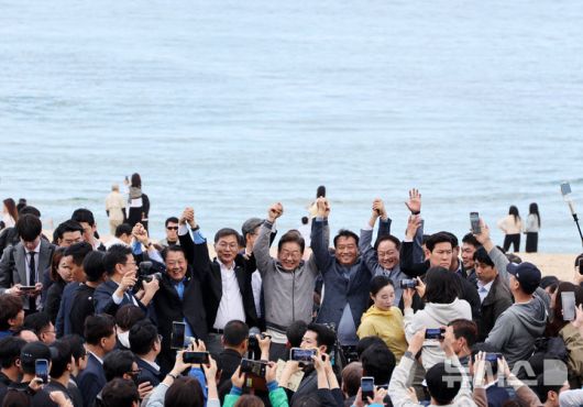 [강릉=뉴시스] 조성우 기자 = 민심을 청취하는 '경청 투어'에 나선 이재명 더불어민주당 대선후보가 3일 강원도 강릉시 안목해변 카페거리에서 이병주 의원, 이 후보 직속 이광재 국가미래정책위원회 공동위원장 등과 손을 맞잡고 주민들과 관광객들에게 인사하고 있다. 2025.05.03. xconfind@newsis.com