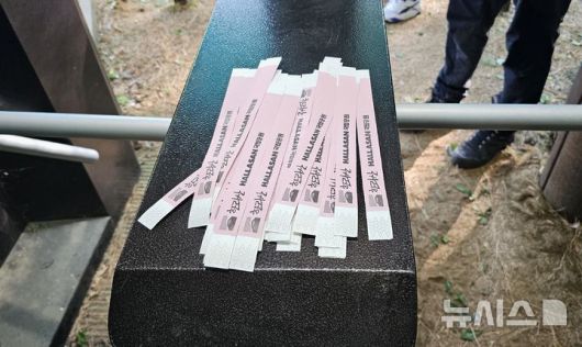 [제주=뉴시스] 임재영 기자 = 4일 오전 한라산국립공원 관음사탐방로 입구에서 탐방객에게 나눠주고 있는 '띠지'. 2025.05.04. ijy788@newsis.com