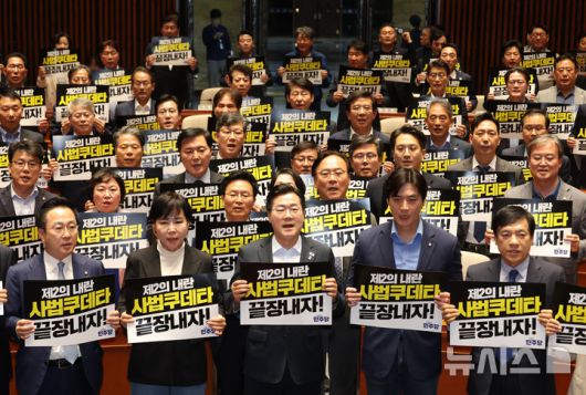 [서울=뉴시스] 고승민 기자 = 더불어민주당 박찬대 대표 직무대행 겸 원내대표와 의원들이 4일 서울 여의도 국회에서 열린 긴급 의원총회에서 피켓을 들고 구호를 외치고 있다. 2025.05.04. kkssmm99@newsis.com