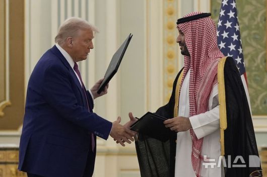 [리야드=AP/뉴시스] 도널드 트럼프(왼쪽) 미국 대통령과 무함마드 빈 살만 사우디아라비아 왕세자가 지난 13일(현지 시간) 리야드 왕궁에서 열린 협정서 서명식을 마치고 이를 교환하며 악수하고 있다. 2025.05.16.
