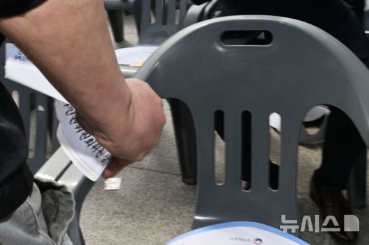 [광주=뉴시스] 이영주 기자 = 5·18민주화운동 45주기를 맞은 18일 오전 광주 북구 운정동 국립5·18민주묘지 기념식장에서 한 5·18단체 회원이 안창호 국가인권위원장의 지정석에 붙여진 이름·직함 스티커를 떼어내고 있다. 2025.05.18. leeyj2578@newsis.com