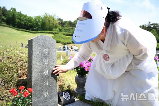 [광주=뉴시스] 김혜인 기자 = 광주5·18민주화운동 45주년 기념식이 열린 18일 오전 광주 북구 운정동 국립 5·18민주묘지에서 5·18희생자의 아내가 남편 김영철 열사의 묘역을 찾아 묘비를 닦고 있다. 2025.05.18. hyein0342@newsis.com