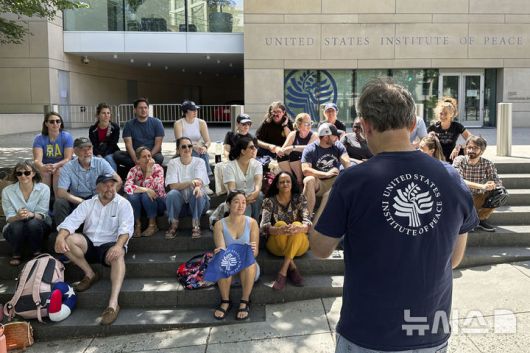 [워싱턴=AP/뉴시스] 트럼프 정부가 연방정부의 기구 축소 공약을 지킨다며 폐쇄한 워싱턴 D.C.의 미 평화연구소 앞에서 5월 19일 직원들이 연방법원의 불법폐쇄 판정 소식을 듣고 자발적으로 모여들어 기쁨을 나누고 있다.  연방법원의 베릴 하월 판사는 트럼프 정부의 평화연구소 해체작업이 불법이라며 중지를 명령했고 21일에는 무스 소장대행을 비롯한 본부 직원 대부분이 다시 출근을 시작했다. 2025. 05. 22.