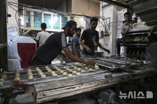 [데이르알발라=AP/뉴시스] 5월 22일 이스라엘이 일부 구호물자의 가자지구 반입을 허용함에 따라 세계식량계획(WFP)이 밀가루를 들여오자, 데이르알발라에서 팔레스타인 주민들이 서둘러 빵을 굽고 있다. 2025.05.25.