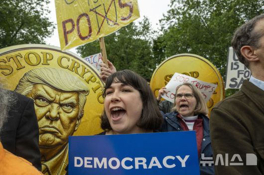 [워싱턴=AP/뉴시스] 아워 레볼루션 소속 활동가들이 22일(현지시간) 버지니아 스털링에 위치한 트럼프 내셔널 골프장에서 로비 활동과 부패에 항의하는 시위를 벌이고 있다. 골프장 안에서는 대통령의 암호화폐 상위 보유자 220명이 트럼프와의 독점 만찬 자리를 위해 총 3억 9400만 달러 이상을 지불했다.