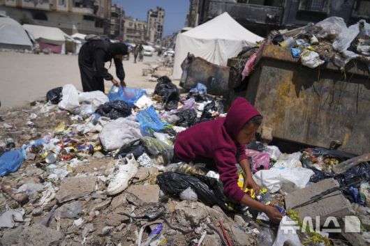 [가자시티=AP/뉴시스] 가자지구 내 팔레스타인 주민들의 절박함이 커지는 가운데 지난 지난 25일(현지 시간) 다섯 자녀를 둔 40세 여성 이슬람 아부 타에마가 가자시티 쓰레기 더미 속에서 빵 한 조각을 줍고 있다. 2025.05.27.