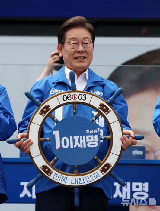 [평택=뉴시스] 조성우 기자 = 이재명 더불어민주당 대선후보가 31일 오후 경기 평택시 배다리생태공원에서 열린 유세에서 '진짜 대한민국' 이라고 적힌 조타기를 들고 있다. 2025.05.31. xconfind@newsis.com