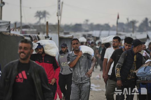 [칸유니스=AP/뉴시스] 3일(현지 시간) 가자지구 칸유니스에서 팔레스타인 주민들이 '가자 인도주의 재단'이 배급한 식량을 얻어 돌아가고 있다. 2025.06.04.