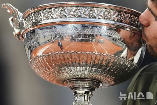 [파리=AP/뉴시스] 카를로스 알카라스(2위·스페인)가 8일(현지 시간) 프랑스 파리 롤랑가로스에서 열린 프랑스오픈 남자 단식 정상에 올라 트로피를 들고 입 맞추고 있다. 알카라스는 결승전에서 얀니크 신네르(1위·이탈리아)와 5시간 29분 대접전 끝에 3-2(4-6 6-7 6-4 7-6 7-6) 역전승을 거두고 대회 2연패를 달성했다. 2025.06.09.