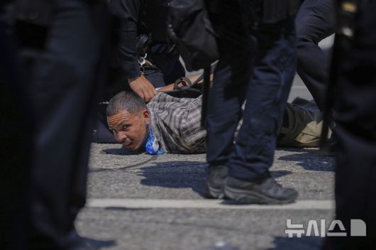 [로스앤젤레스=AP/뉴시스] 8일(현지 시간) 미 캘리포니아주 로스앤젤레스 도심에서 이민세관단속국(ICE)의 불법 이민자 단속 및 체포에 항의하던 시위 참가자가 경찰에 체포되고 있다. 도널드 트럼프 대통령은 불법 이민자 단속에 항의하는 시위에 참여하는 사람들은 마스크를 착용해서는 안 된다고 밝혔다. 2025.06.09.