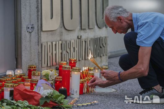 [그라츠=AP/뉴시스] 10일(현지 시간) 오스트리아 그라츠의 한 고등학교에서 총기 난사 사건이 발생한 후 한 남성이 학교 입구에서 희생자를 위한 촛불을 켜고 있다. 2025.06.11.