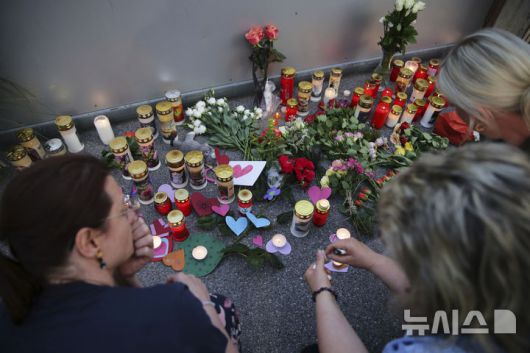 [그라츠=AP/뉴시스] 10일(현지 시간) 오스트리아 그라츠의 한 고등학교에서 총기 난사 사건이 발생한 후 한 남성이 학교 입구에 희생자를 추모하는 꽃이 놓여져 있다. 2025.06.11.